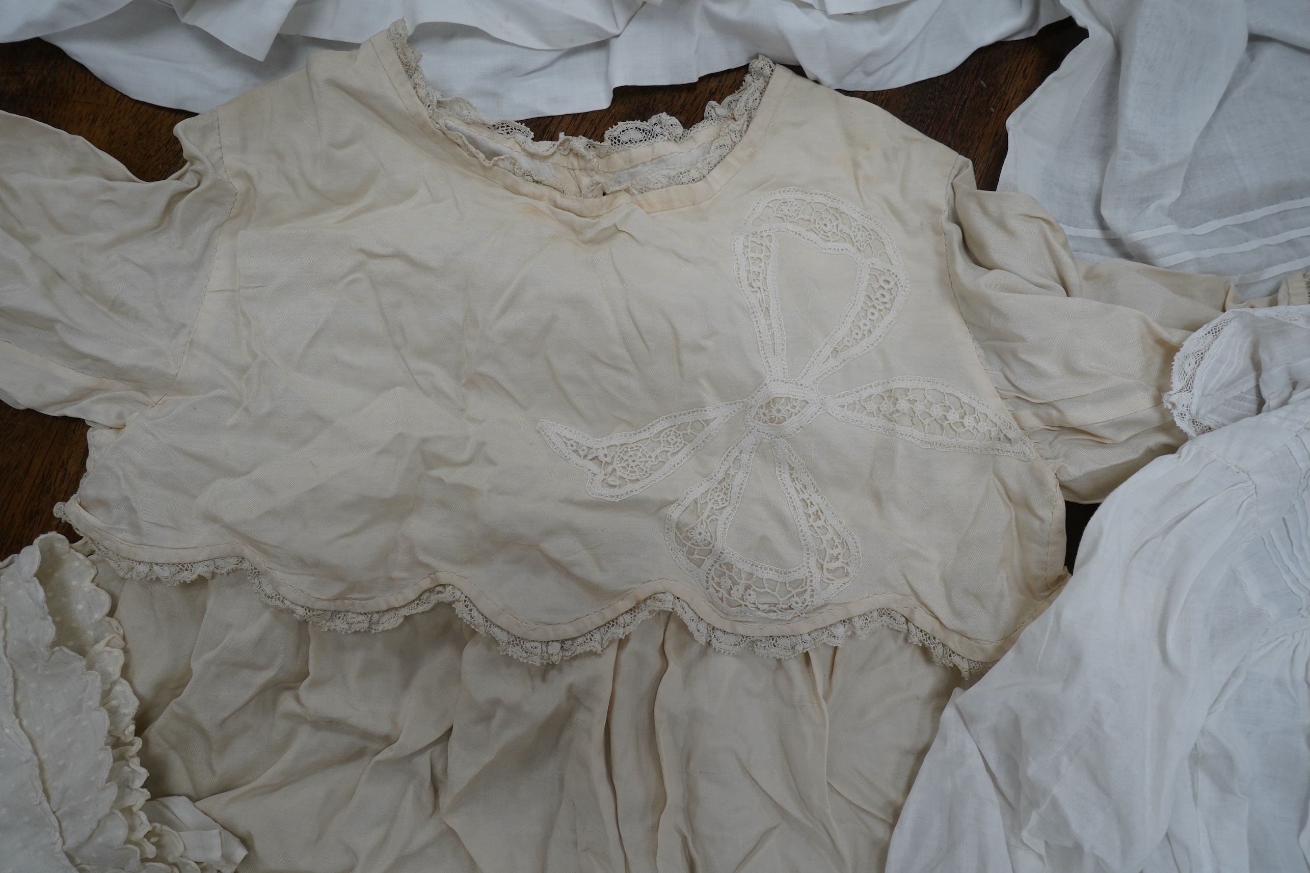 An early 20th century cream silk young girls day dress, together with six similar sized cotton and fine lawn day dresses and a bonnet, all dresses worked with tucking, feather stitching, some lace edged, the bonnet made